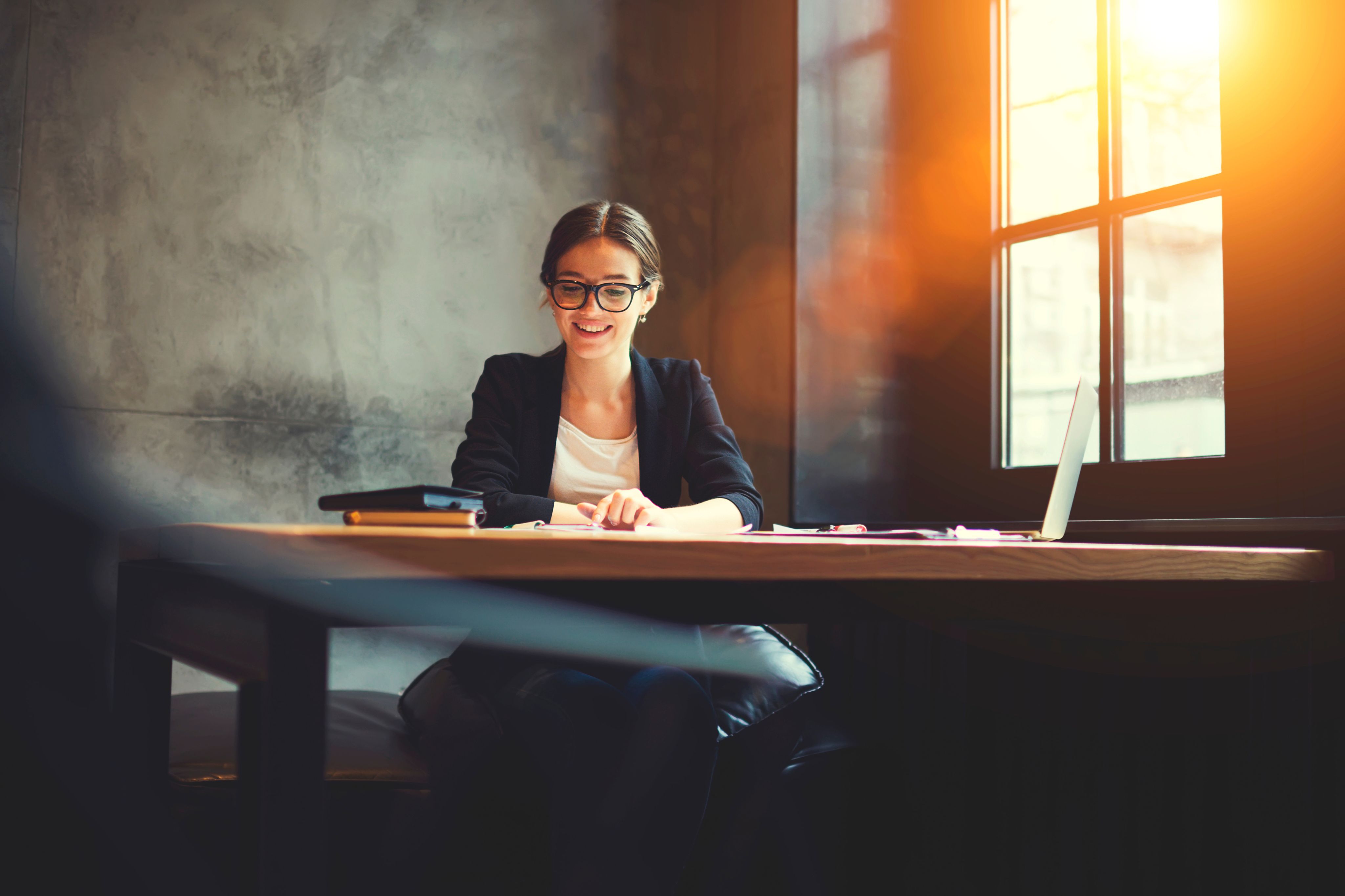 Kvinne på kontoret som smiler mens hun jobber